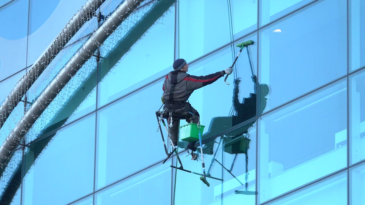 why-choose-us Window cleaner works on a high-rise glass building, ensuring spotless results.